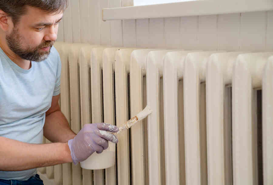 A man carefully painting a radiator